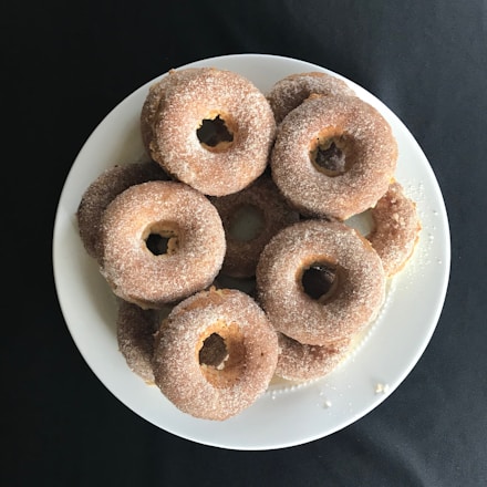 Close-up of a beautifully arranged plate with mini donuts and hotcakes on a cream-colored table.