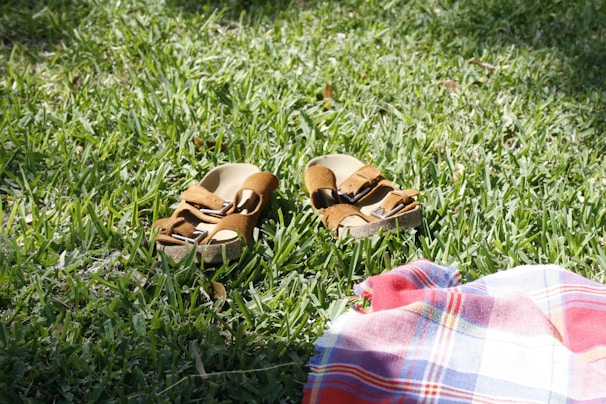 A pair of colorful recycled-material sandals displayed outdoors on green grass