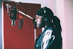 A candid shot of an artist recording in the studio, headphones on, deeply focused.