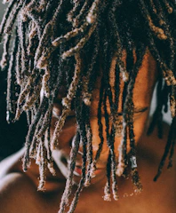 Artistic photo of textured hair styled in dreadlocks with natural pomade beside it.