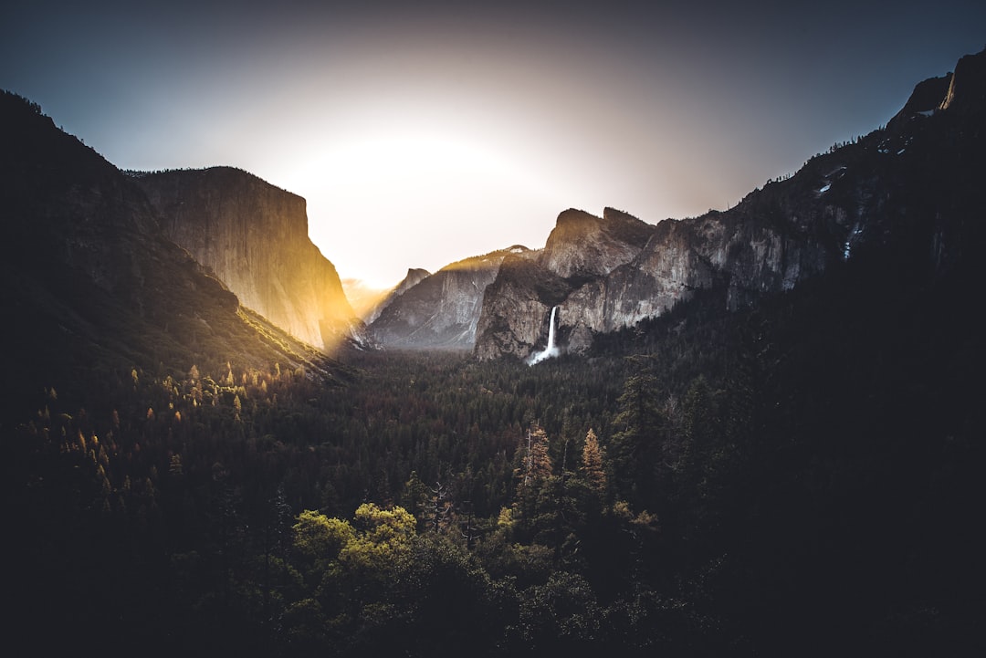waterfalls on mountain near mountains and forest,