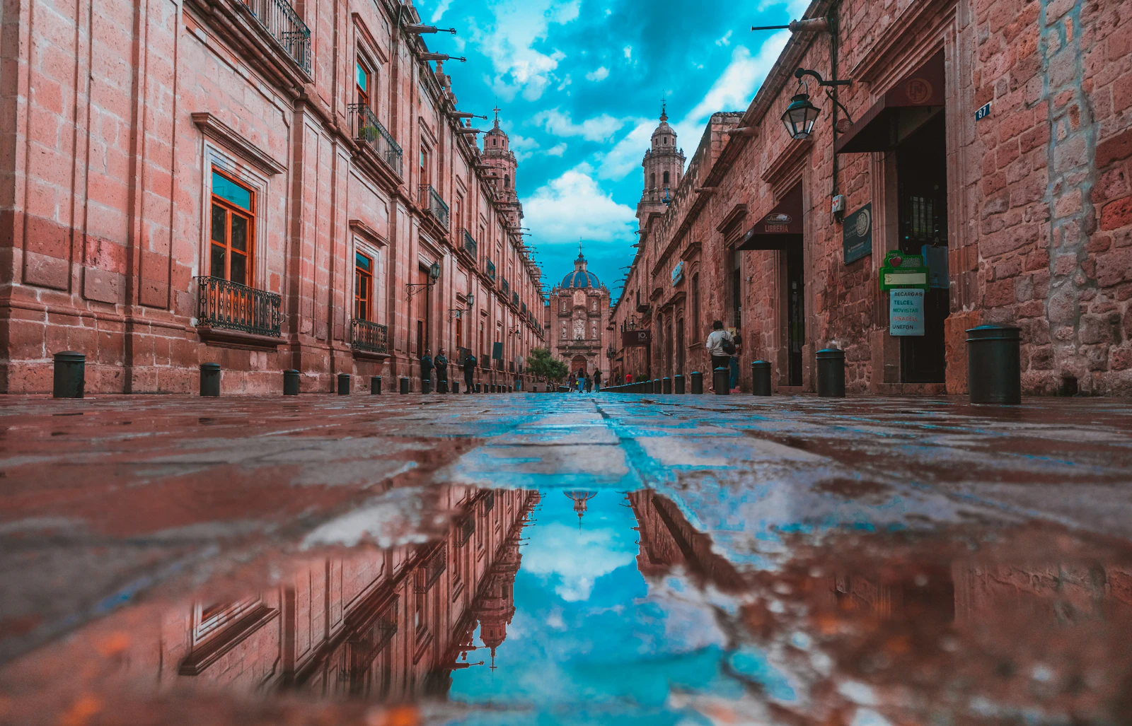 A wet alley of pink stone reflecting the sky in Morelia