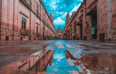 A wet alley of pink stone reflecting the sky in Morelia