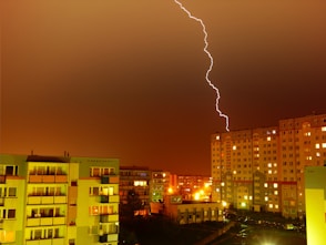 aerial photography of buildings and road under cloudy skies with lightning