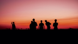 Grainy, moody photo of the team gathered around their bikes, sharing a moment at sunset.