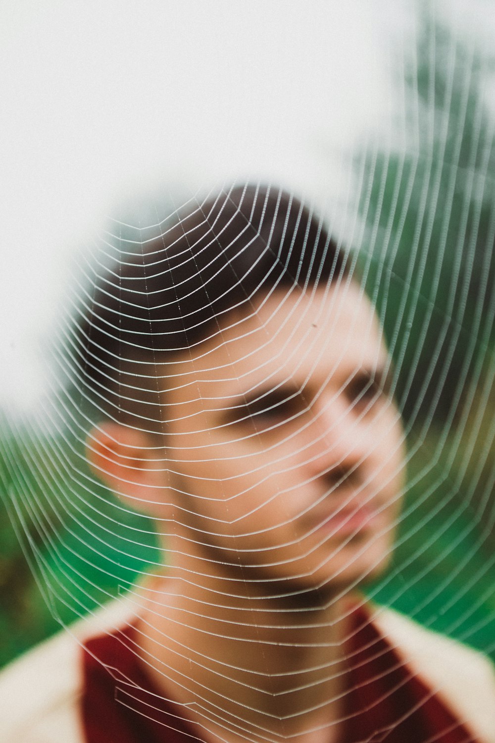 a man is looking at the camera through a spider web