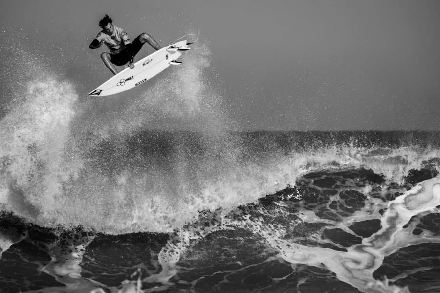 A surfer launching off a breaking wave in black and white
