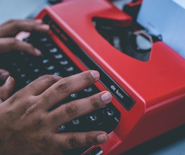 person typing on red typewriter