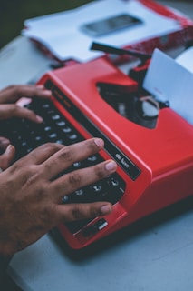 person typing on red typewriter