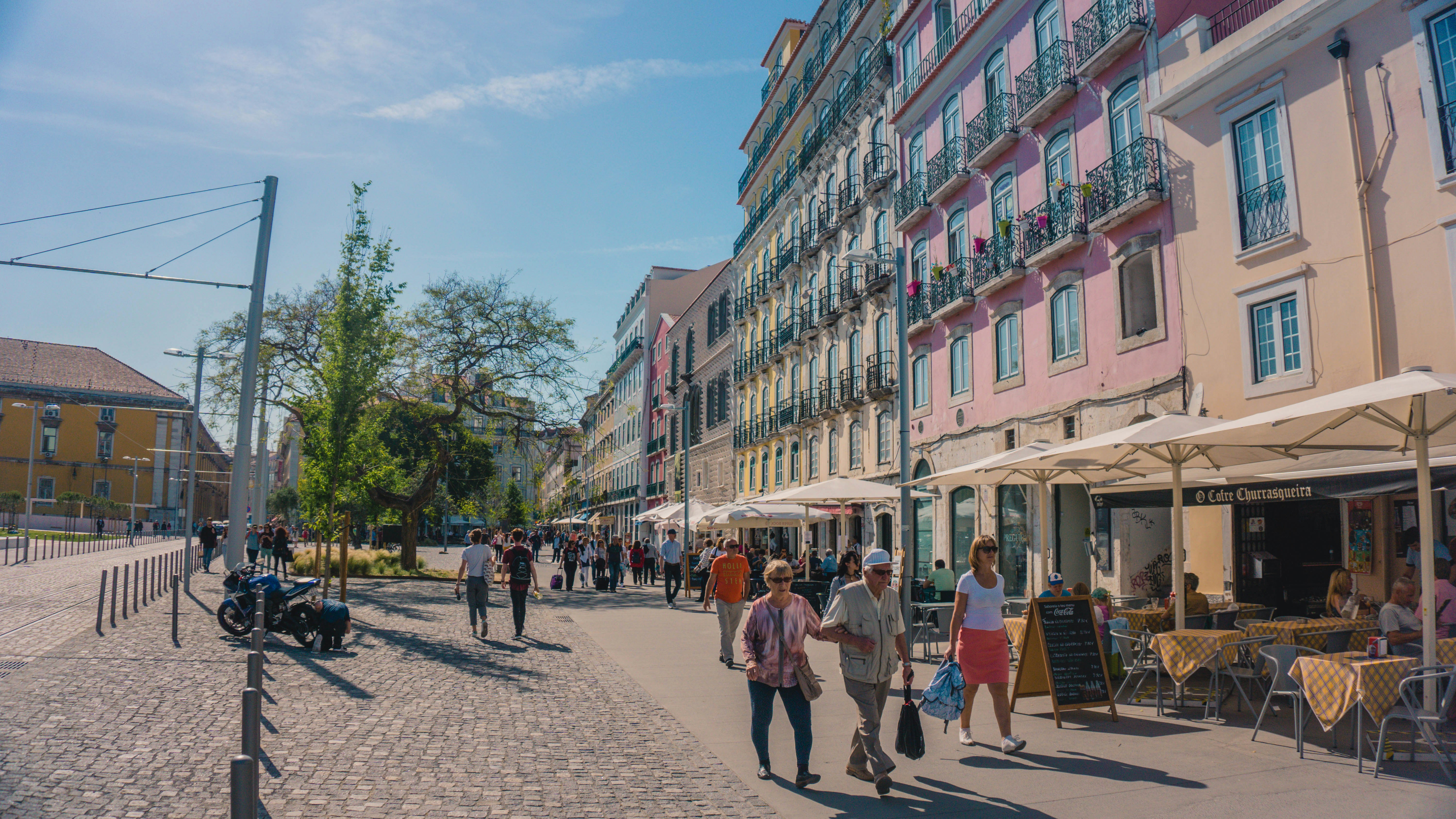 A lively street scene in Bucharest with colorful buildings and people enjoying a sunny day.