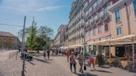 A group of friends laughing on a European city street lined with colorful buildings.
