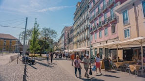 A lively city square in Europe filled with people enjoying a sunny afternoon café scene