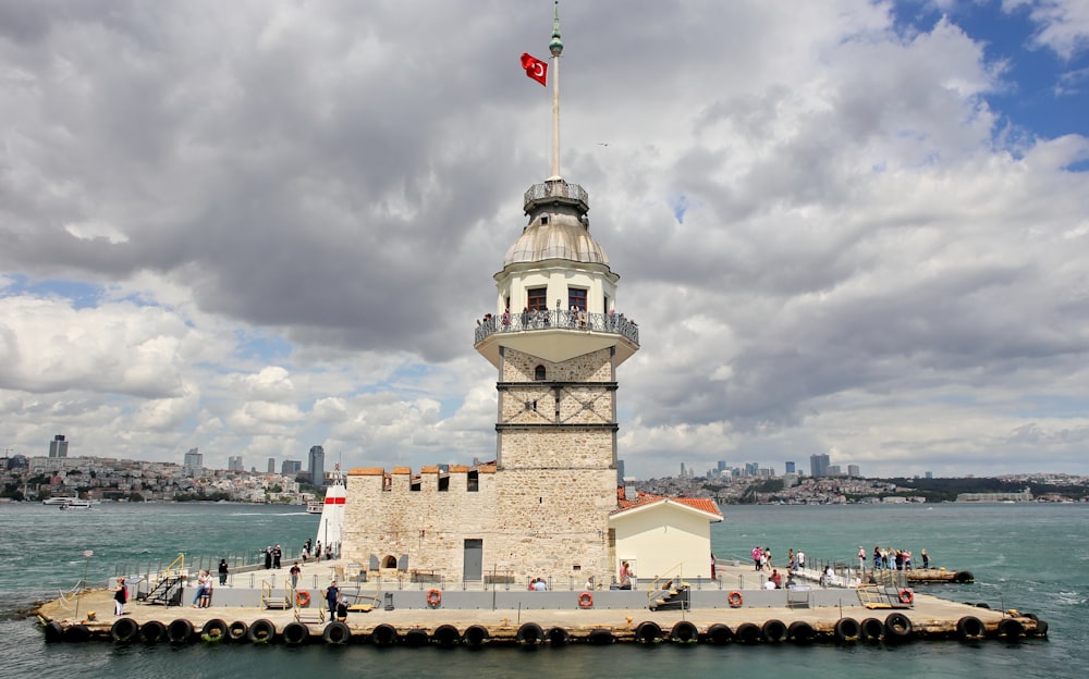 Persone vicino alla torre bianca in mezzo al mare durante il giorno