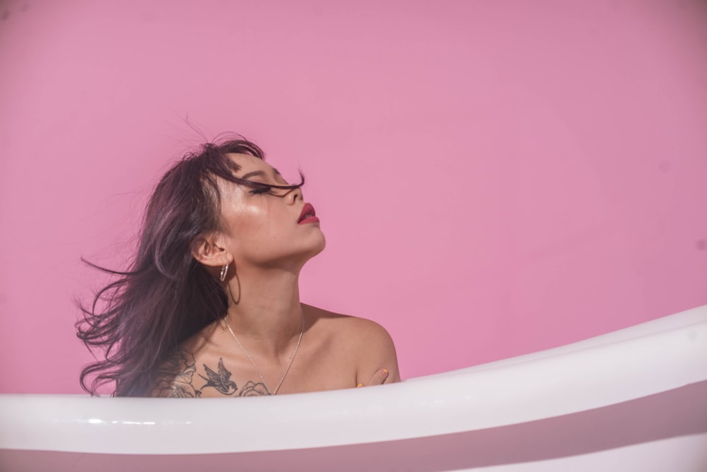 a woman in a bathtub with her hair blowing in the wind