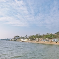 A cozy seaside mobile home with a bright blue sky and calm ocean in the background.