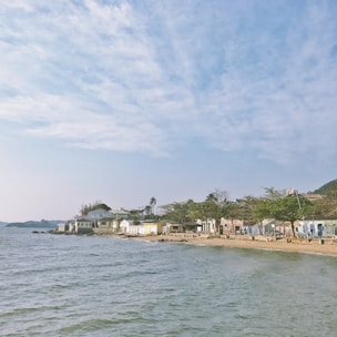 A cozy seaside mobile home with a bright blue sky and calm ocean in the background.