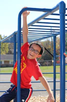 Close-up of a child with bright blue frames, playing in a sunny park.