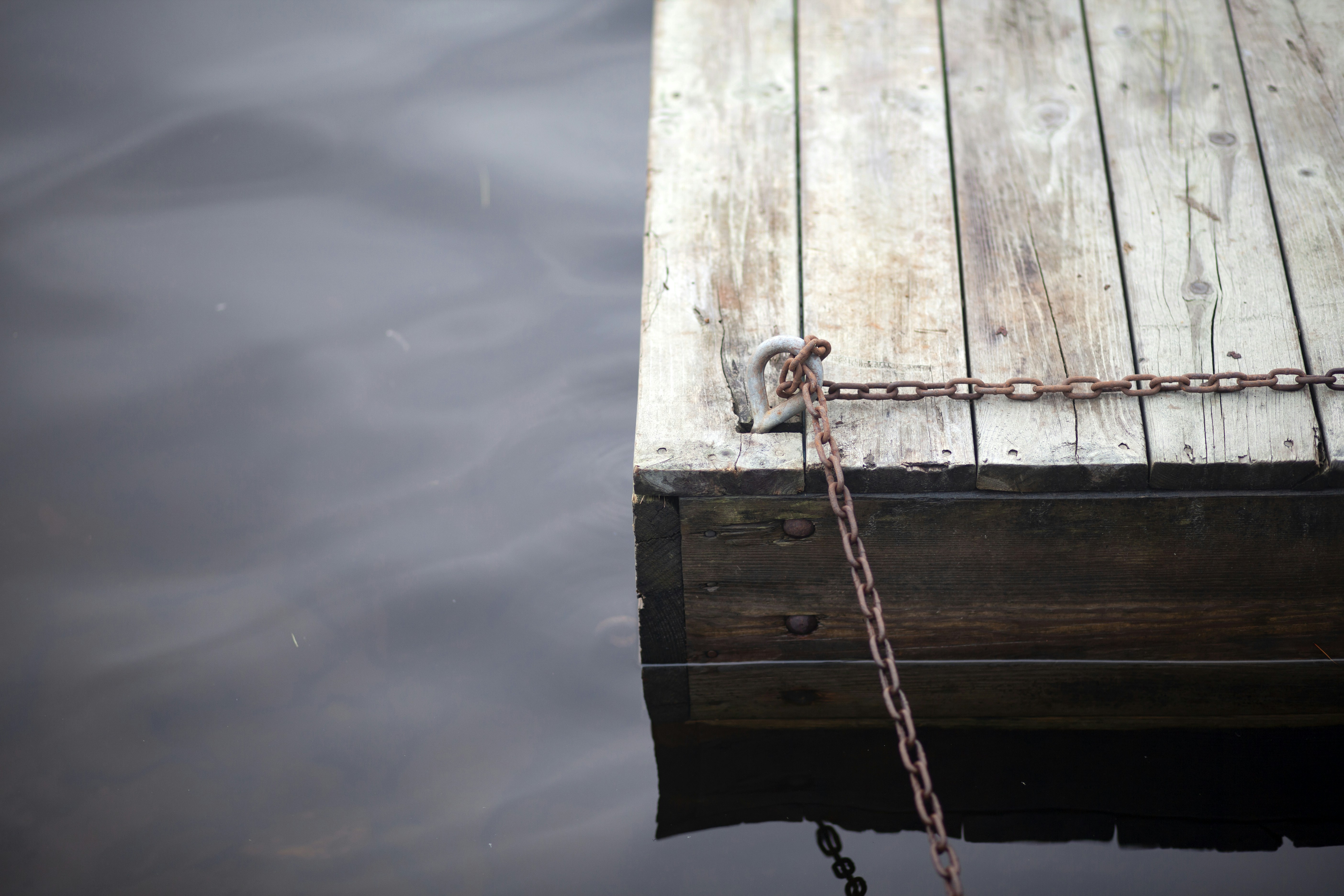 On an overcast day, I saw this chain going out onto a small, worn dock. No boats, no splashing - just quiet.