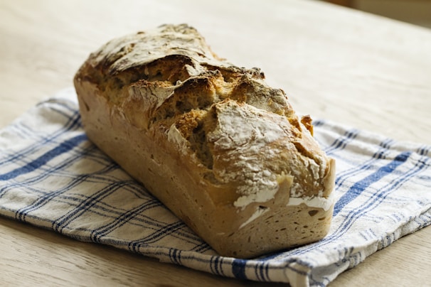 Freshly baked bread with a golden crust resting on a pastel blue cloth, evoking a cozy kitchen atmosphere.
