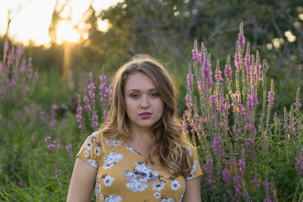 woman standing behind purple petaled flowers during daytime