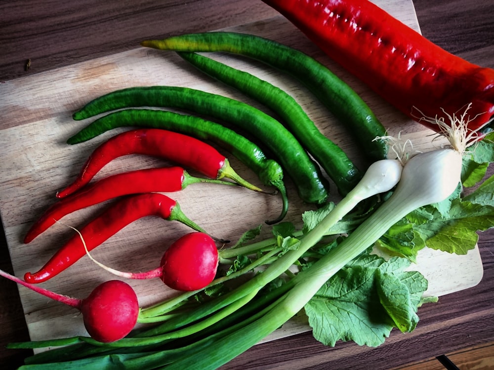 red and green chilis and red bell pepper on brown chopping board