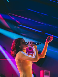 A lively group of friends singing passionately around a microphone at a Krackin Karaoke party with yellow and black decorations.