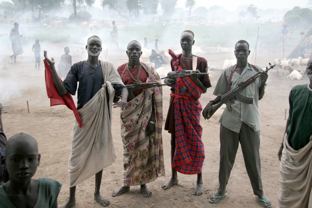 four men holding assault rifles