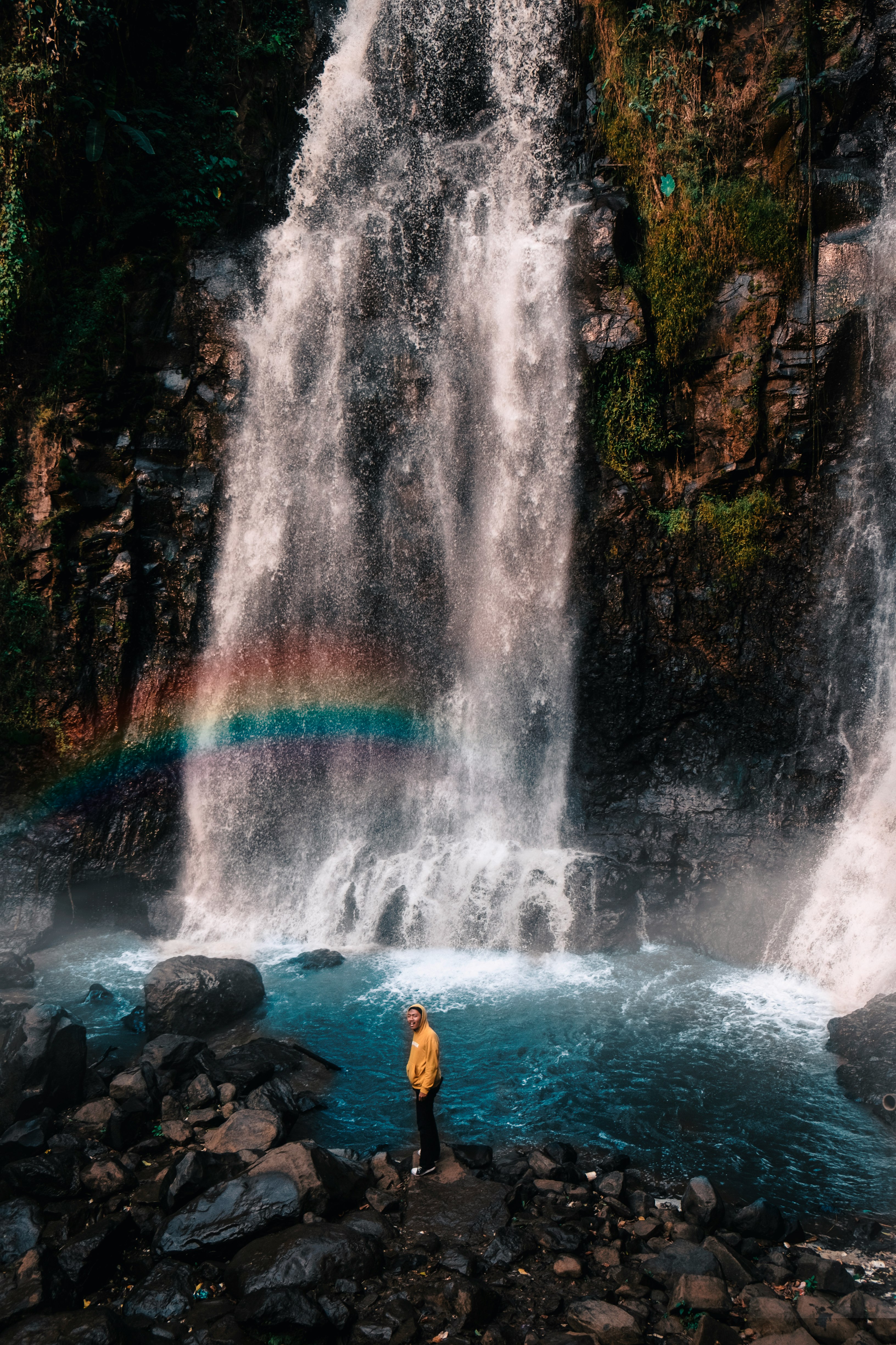 man standing on rock near waterfalls