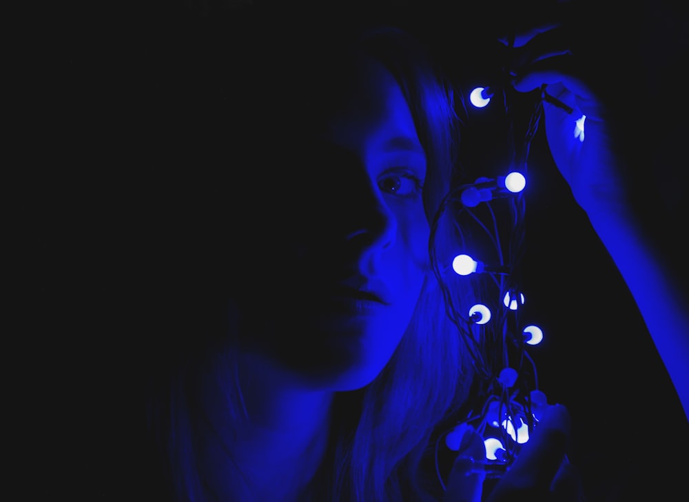 woman holding blue string lights