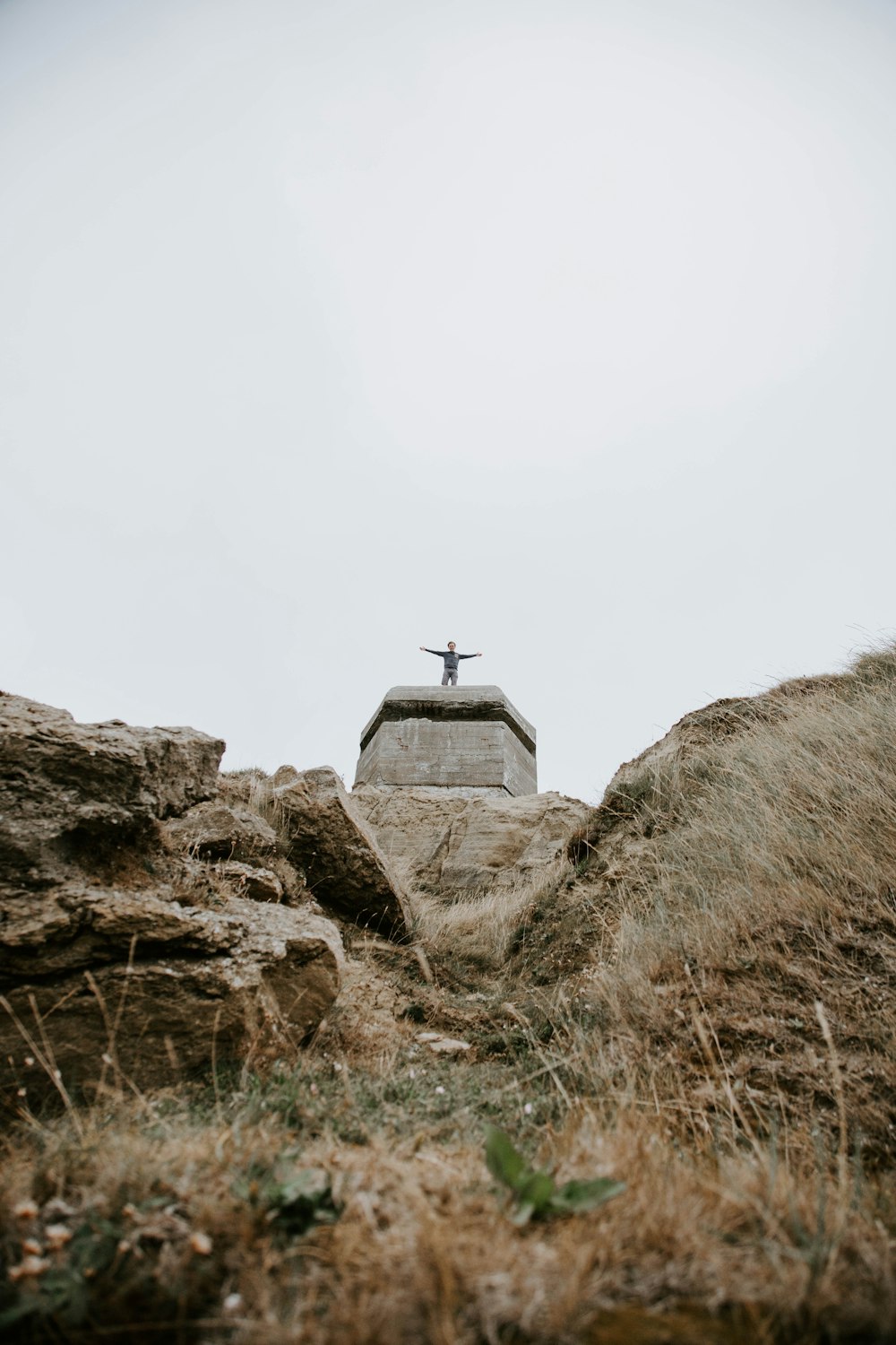 low-angle photography of man standing on stone with arms wide-open statue