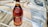 A bottle of brandy with a maroon and gold label is placed on a tan paper surface. The bottle is surrounded by packaging material including bubble wrap and ropes.