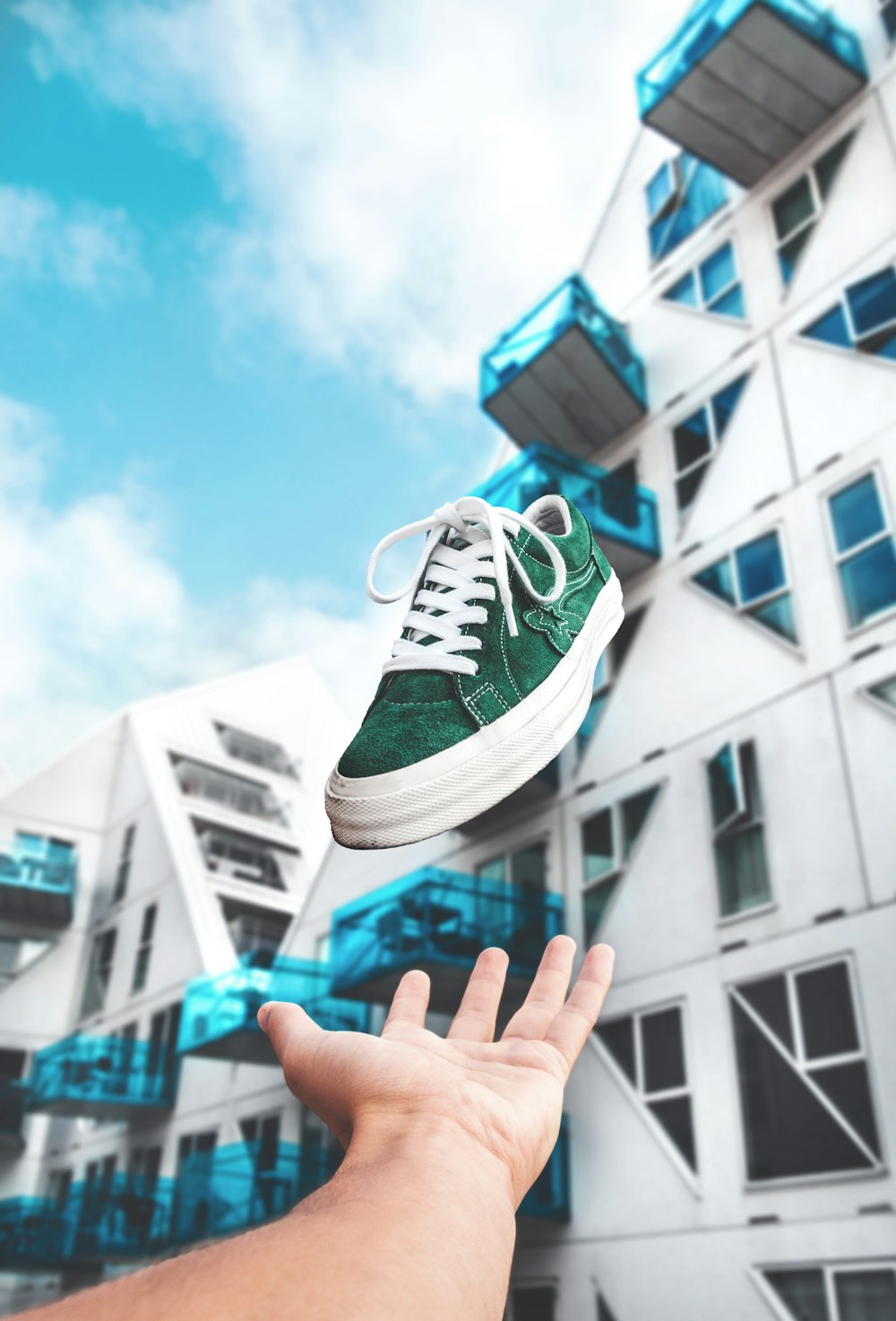 person throwing green and white low-top sneaker at daytime