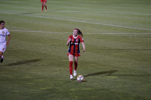 Close-up of a young female soccer player confidently dribbling the ball during a match.