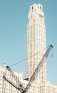 A wide shot of a commercial building rising with cranes against a clear blue sky.
