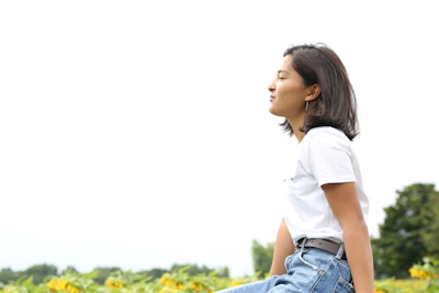 A relaxed person sitting in nature, eyes closed, embracing mindfulness.