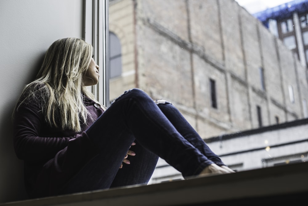 Mujer sentada en la ventana mirando el cielo