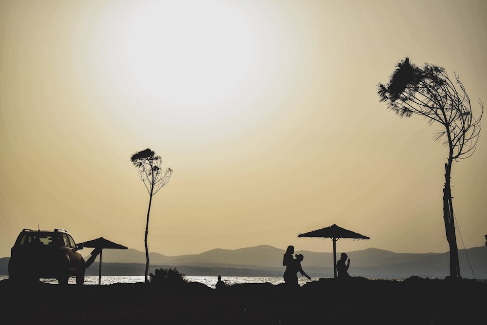 silhouette of three person standing near sea
