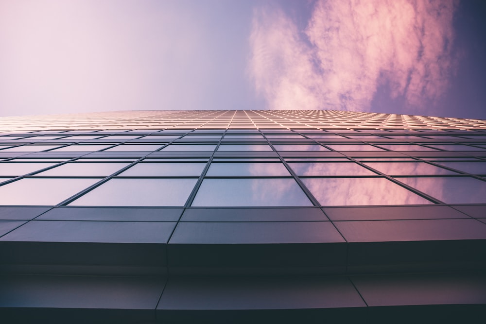 low angle photography of glass window high-rise building under white and blue cloudy skies