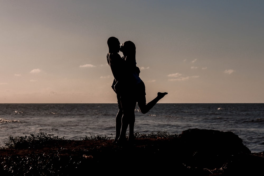 silhouette of kissing couples near sea
