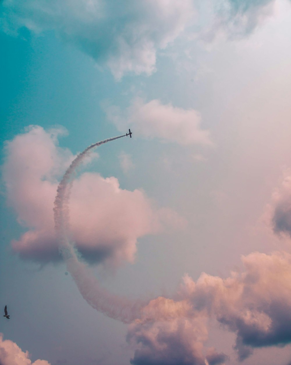 low angle photography of plane flying at high altitude with track of smoke during daytime