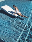 woman lying on white lounge chair in the middle of pool