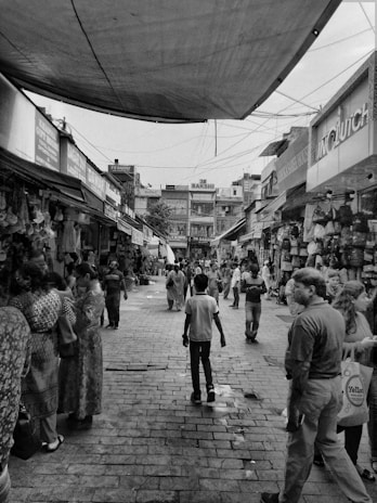 A busy street market in the USA with various price signs visible on stalls and stores.