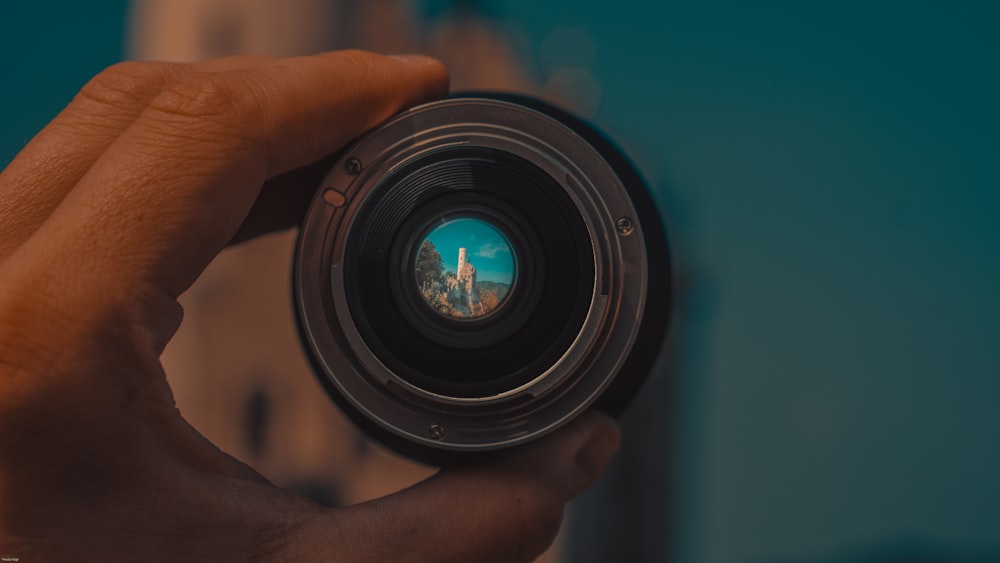 person holding round black camera lens