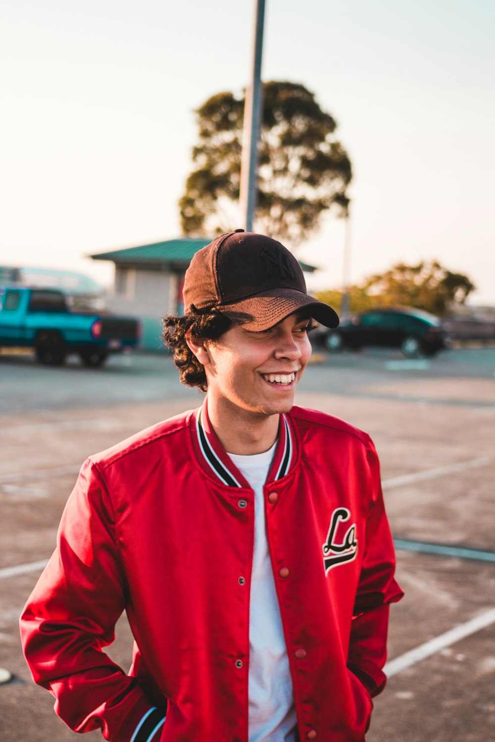 man in r ed letterman jacket standing near car