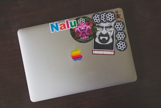 A laptop covered in various artistic stickers.