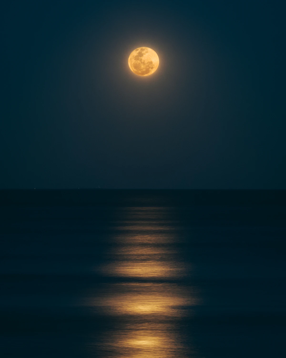 A bright full moon over a still body of water at night, the peak phase that marks the traditional harvest and crystal-cleansing window