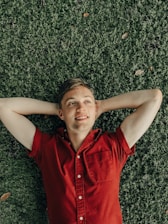 smiling man laying on green grass