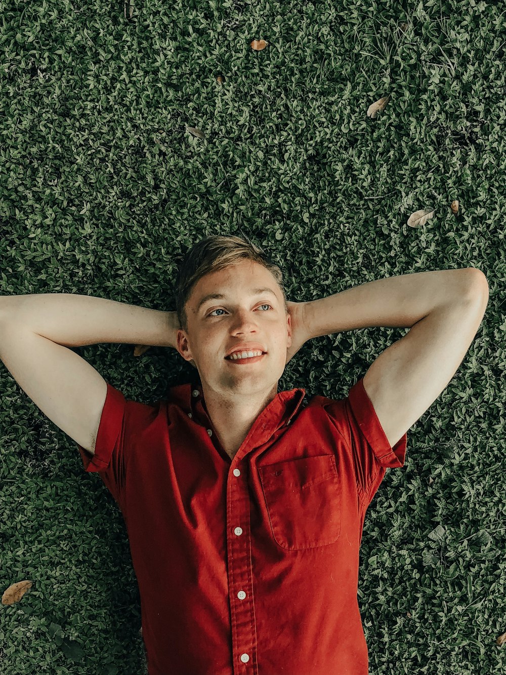 smiling man laying on green grass