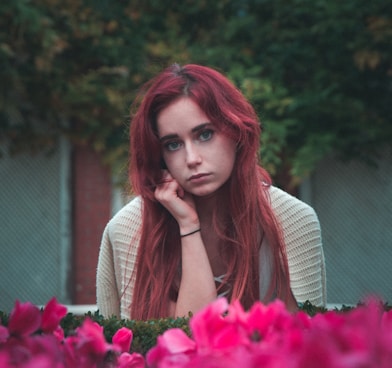 woman wearing grey shirt near pink petaled flowers during daytime