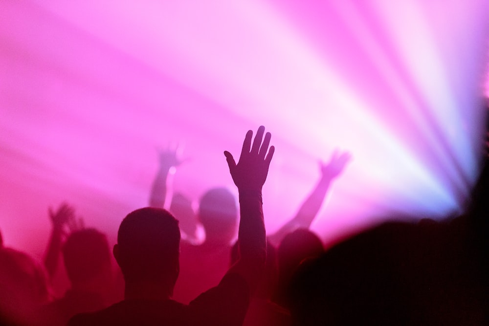 a crowd of people with their hands up in the air